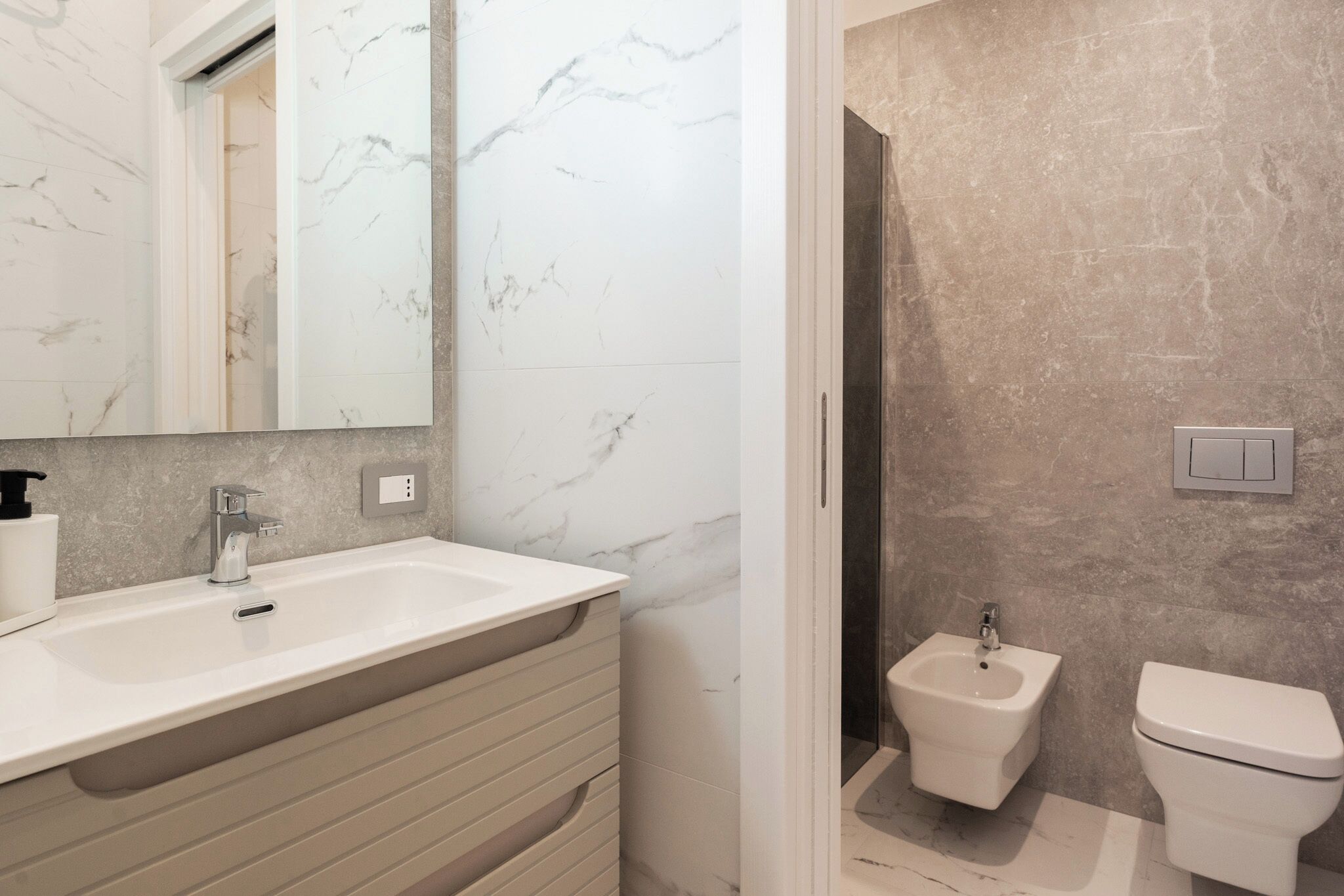 A bathroom with a white marble sink, a bidet, and a toilet.
