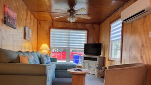 A cozy living room with a sofa, a coffee table, a television, and a ceiling fan. - Escape to this charming beach cottage along the coast of Broadkill Beach (Milton)