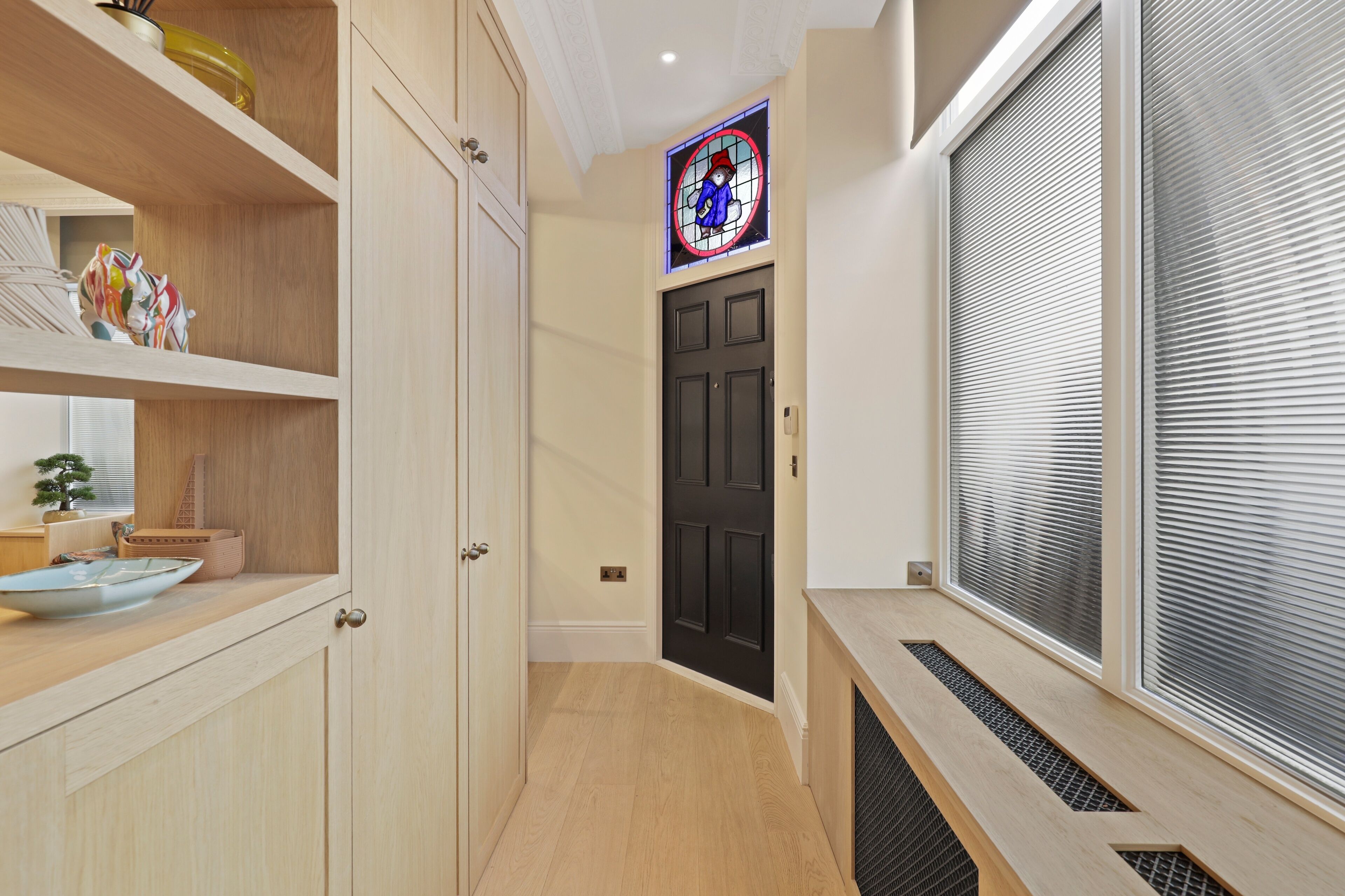 Una cucina moderna con mobili in legno, una porta nera e una finestra con vetrate artistiche.