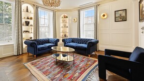 Un salon luxueux avec deux canapés bleus, une table basse en verre et un tapis à motifs.