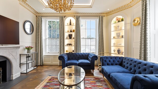Un salon luxueux avec une cheminée, un canapé bleu et une table basse en verre.
