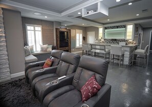 A modern living room with a leather sofa, a stone accent wall, and a kitchen area in the background.