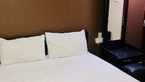 A hotel room with a bed, a nightstand, a mirror, and a wall socket. - New York Guest House and Restaurant Colombo 06 (Colombo)