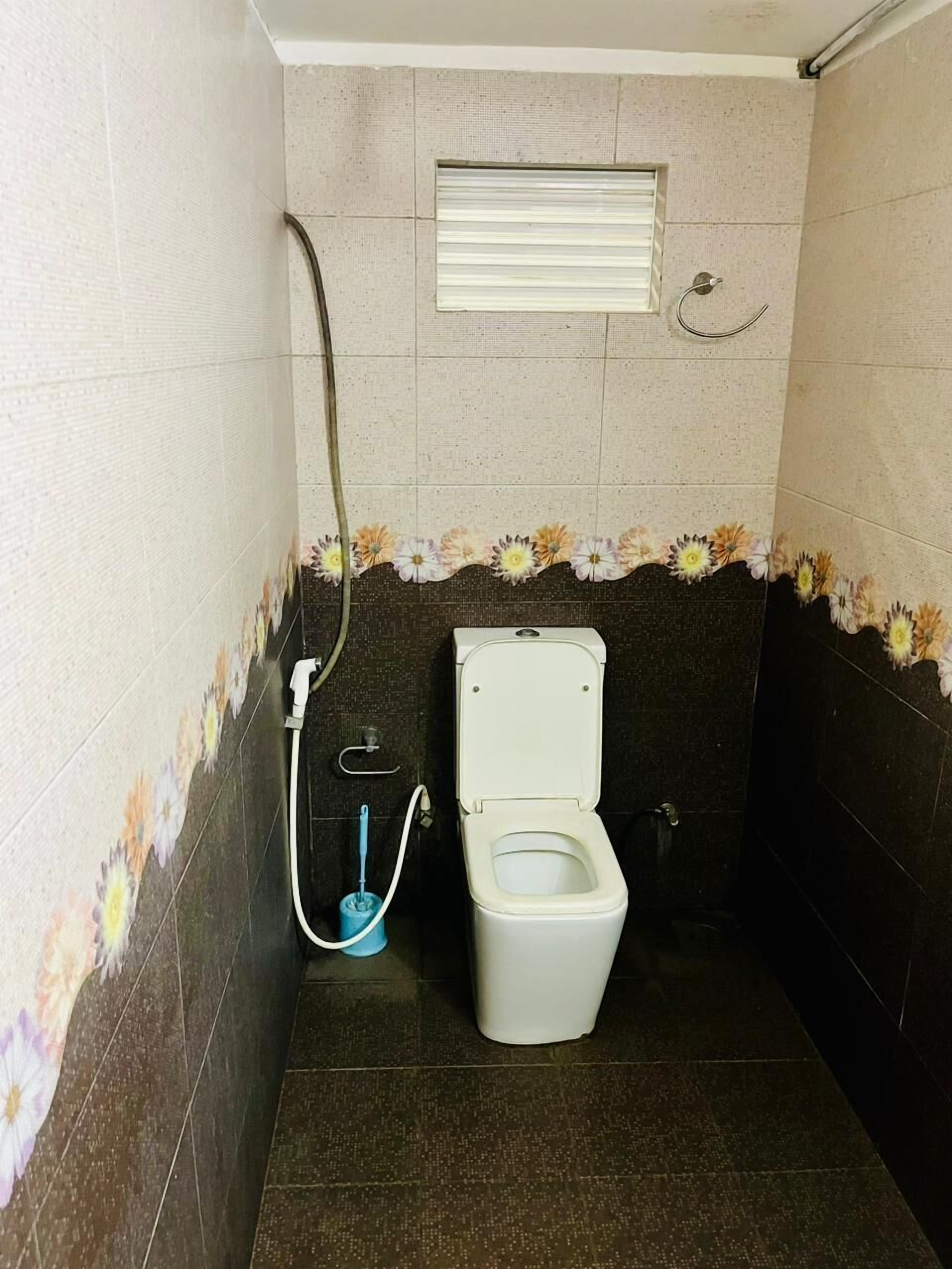 A small bathroom with a toilet, a shower, and a window.