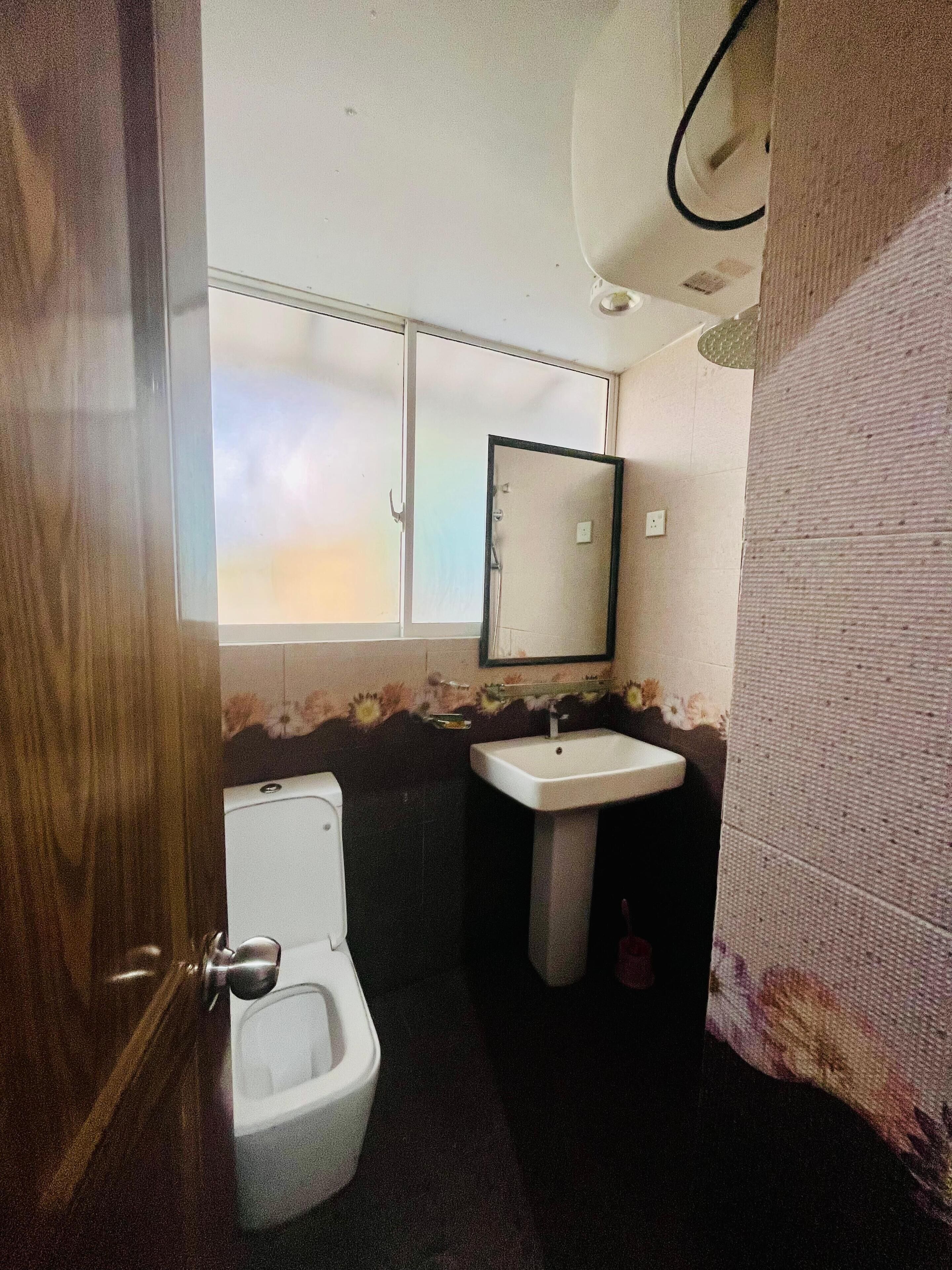 A small bathroom with a toilet, sink, and mirror.