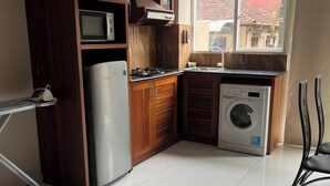 A compact kitchen with a refrigerator, microwave, stove, sink, and washing machine. - New York Guest House and Restaurant Colombo 06 (Colombo)