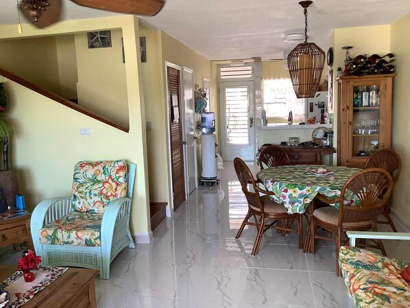 Amplia sala de estar con mesa de comedor, sillas, sofá y cocina al fondo.