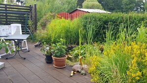 A patio with a table and chairs, surrounded by potted plants and a garden.