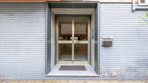 A building entrance with a glass door, a mailbox, and a small step leading up to the door.