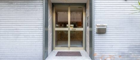 A building entrance with a glass door, a mailbox, and a small step leading up to the door.