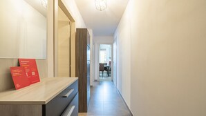 A hallway with a wooden cabinet, a red welcome card, and a view into a dining area.