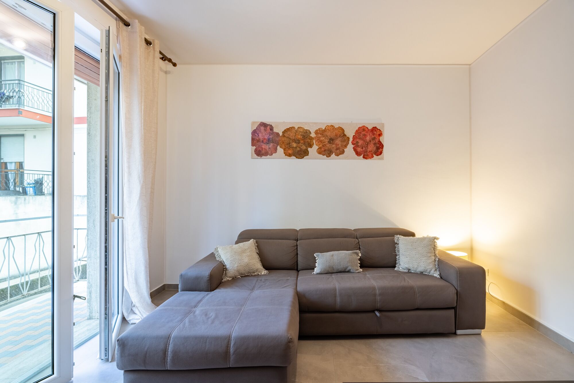 A modern living room with a sectional sofa, a small table, and a wall-mounted artwork.