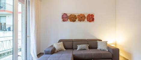 Ein modernes Wohnzimmer mit einem Ecksofa, einem kleinen Tisch und einem an der Wand befestigten Kunstwerk.