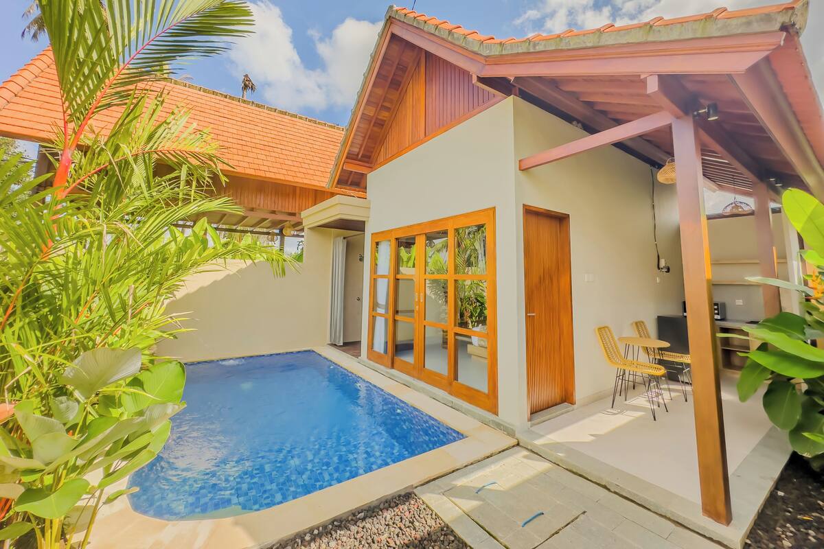 A modern house with a swimming pool, wooden doors, and a covered patio area.