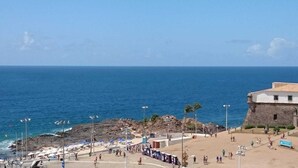 A coastal area with a beach, rocky shoreline, and a historic building.