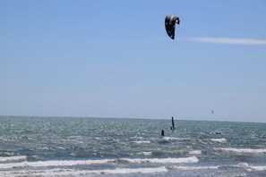 Ein Strand mit blauem Himmel und einer Person, die Windsurfen geht.