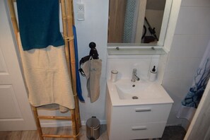 Ein Badezimmer mit Waschbecken, Spiegel, Handtuchhalter und kleinem Mülleimer.