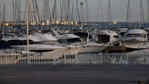 A marina with multiple boats docked, a white fence in the foreground, and a cityscape in the background. - L' Escale, appartement climatisé à 50 mètres de la plage avec WIFI et Box Tv (Fos-sur-Mer)