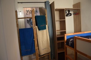 Ein Zimmer mit Etagenbett, Holzschrank und Wäscheständer mit Handtüchern.