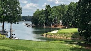 Un parcours de golf avec un plan d’eau, des arbres et un quai où sont amarrés des bateaux.