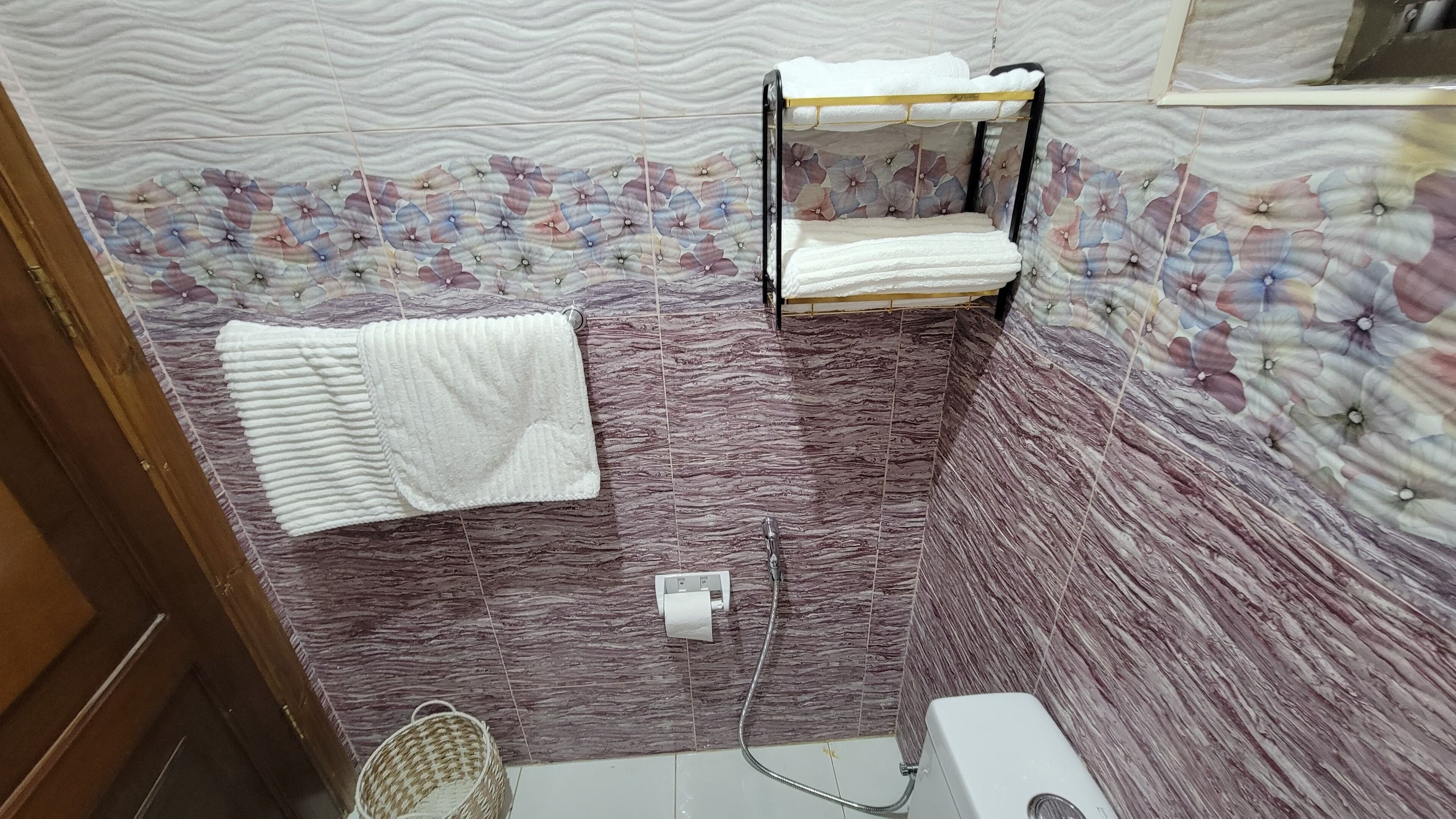 Ein Badezimmer mit Dusche, Handtuchhalter und Toilette.