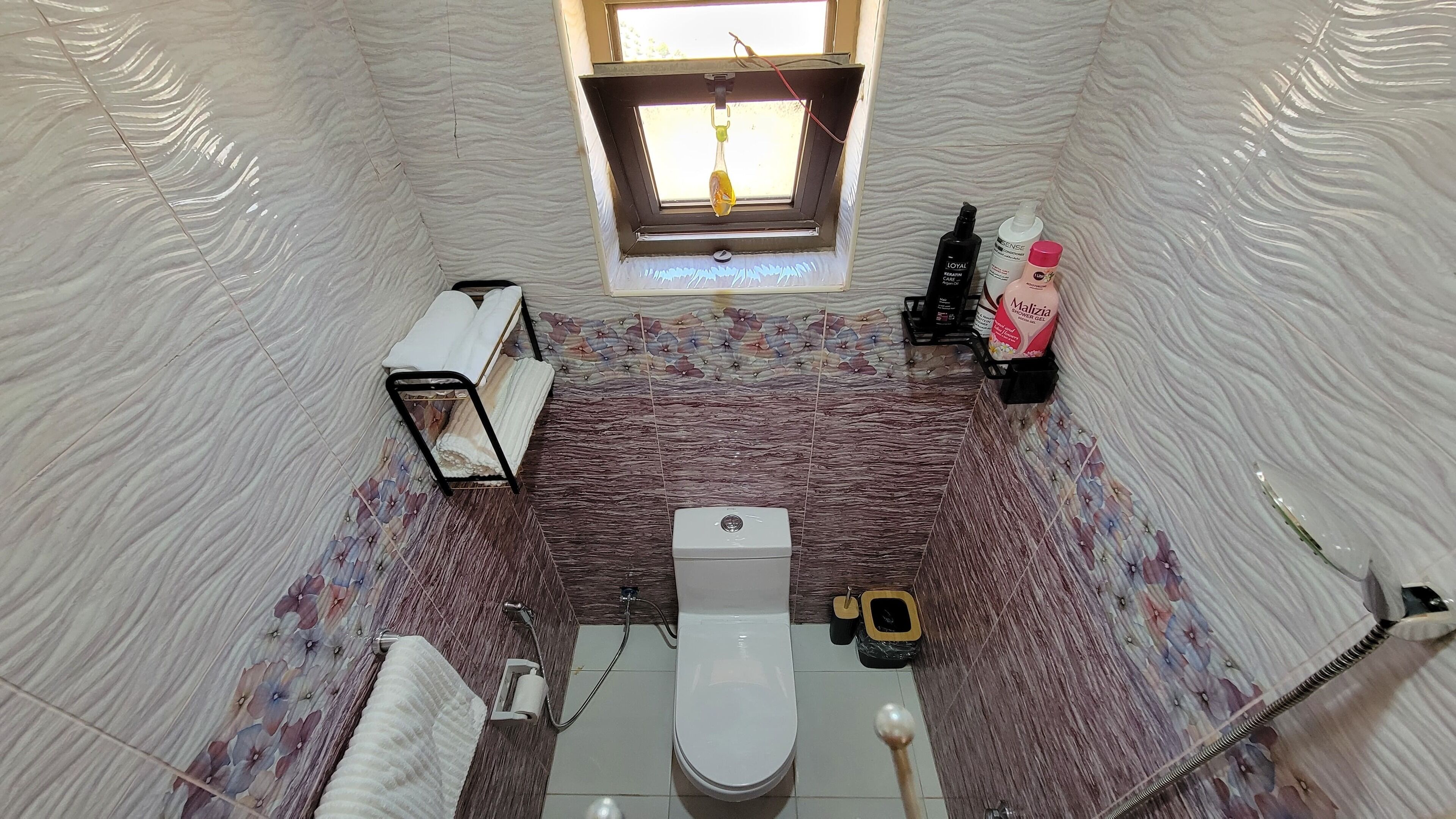 Un bagno compatto con il water, un lavandino, una finestra e una zona doccia.