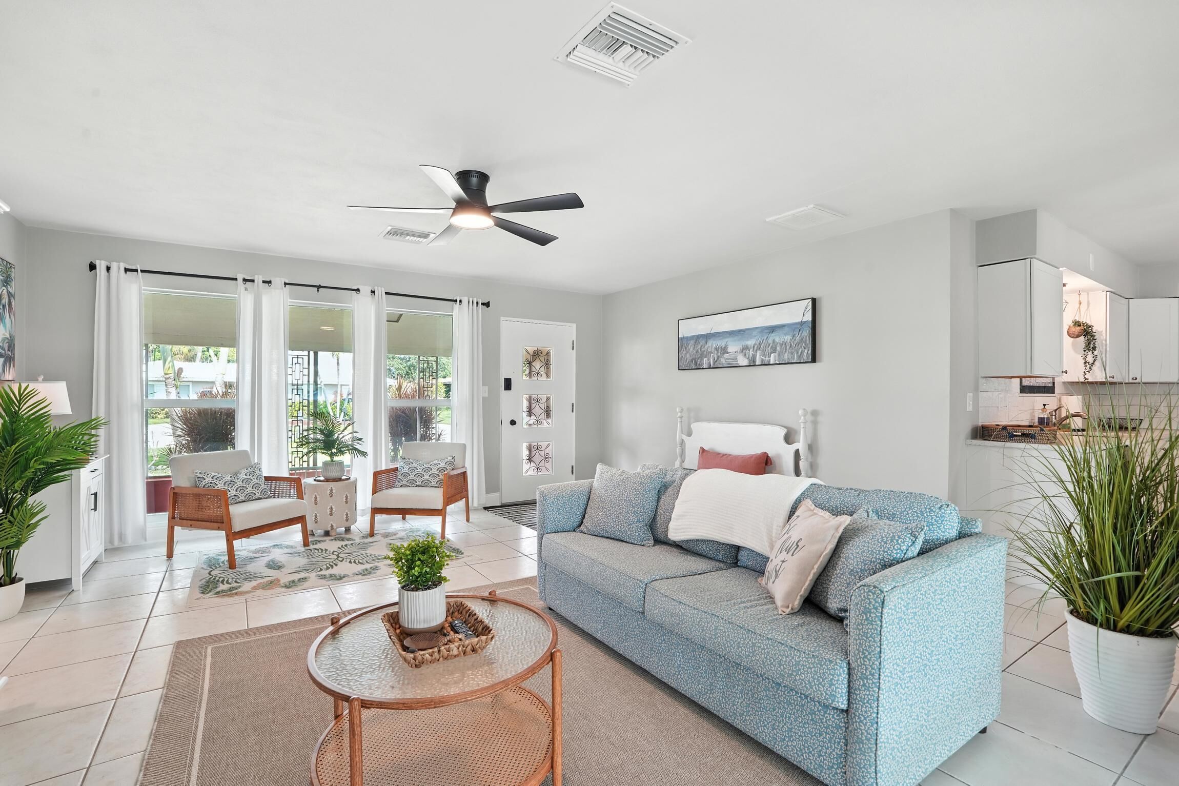 A modern living room with a sofa, chairs, a coffee table, and a ceiling fan.