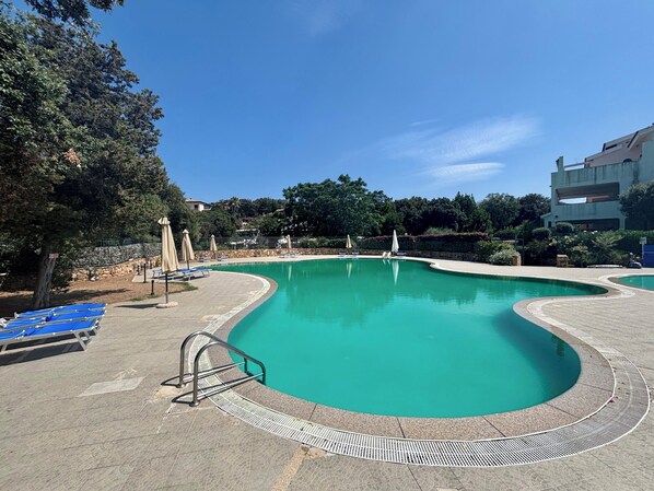 Piscina a l'aire lliure de temporada, para-sols i gandules