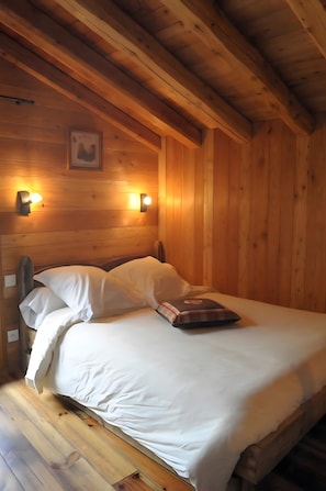 Una camera da letto in stile baita con un letto, due luci a parete e un quadro appeso al muro.