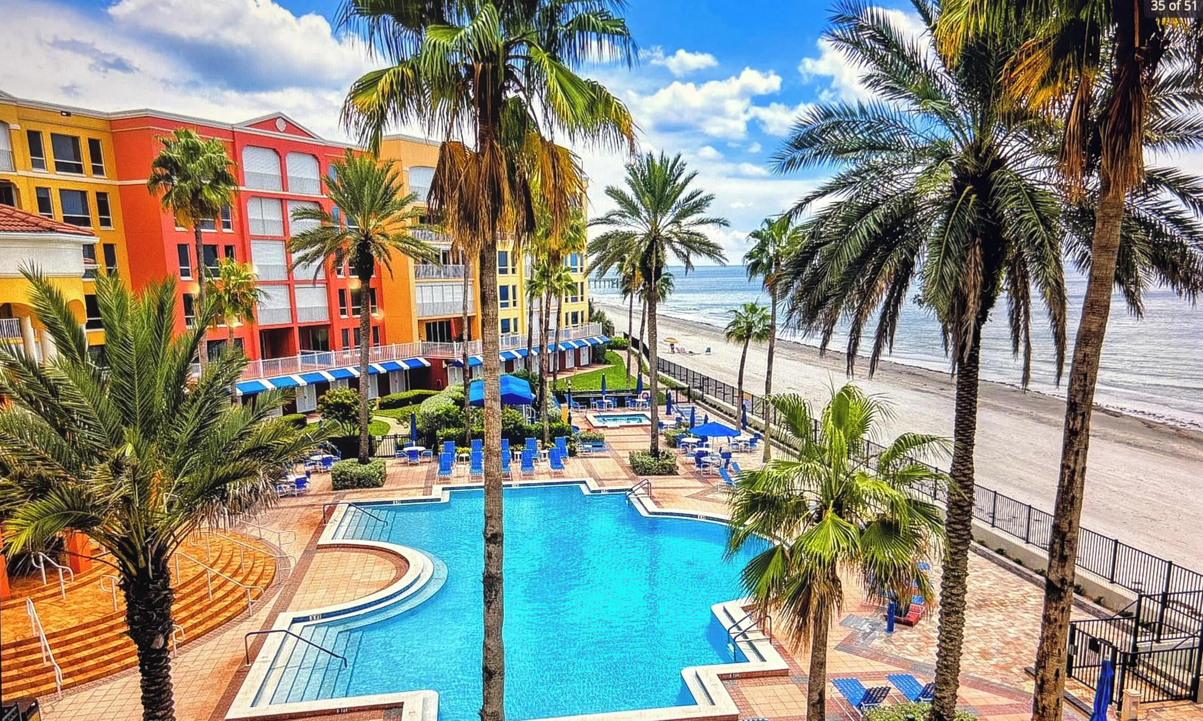 Ein Resort mit großem Pool, Palmen und Blick auf den Strand.