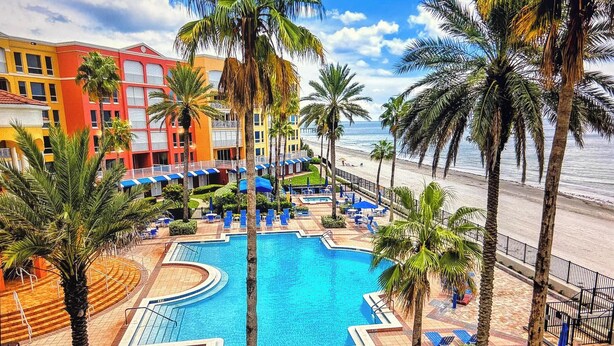 Un resort con una piscina grande, palmeras y vista al mar.