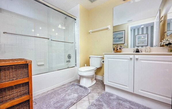 A bathroom with a glass-enclosed shower, a toilet, and a vanity with cabinets.