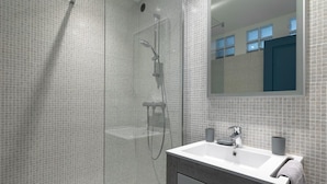 A modern bathroom with a glass shower enclosure, a white sink, and a mirror above the sink.