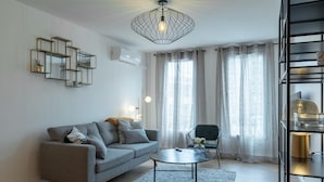 A modern living room with a grey sofa, a round coffee table, and a black metal chandelier.
