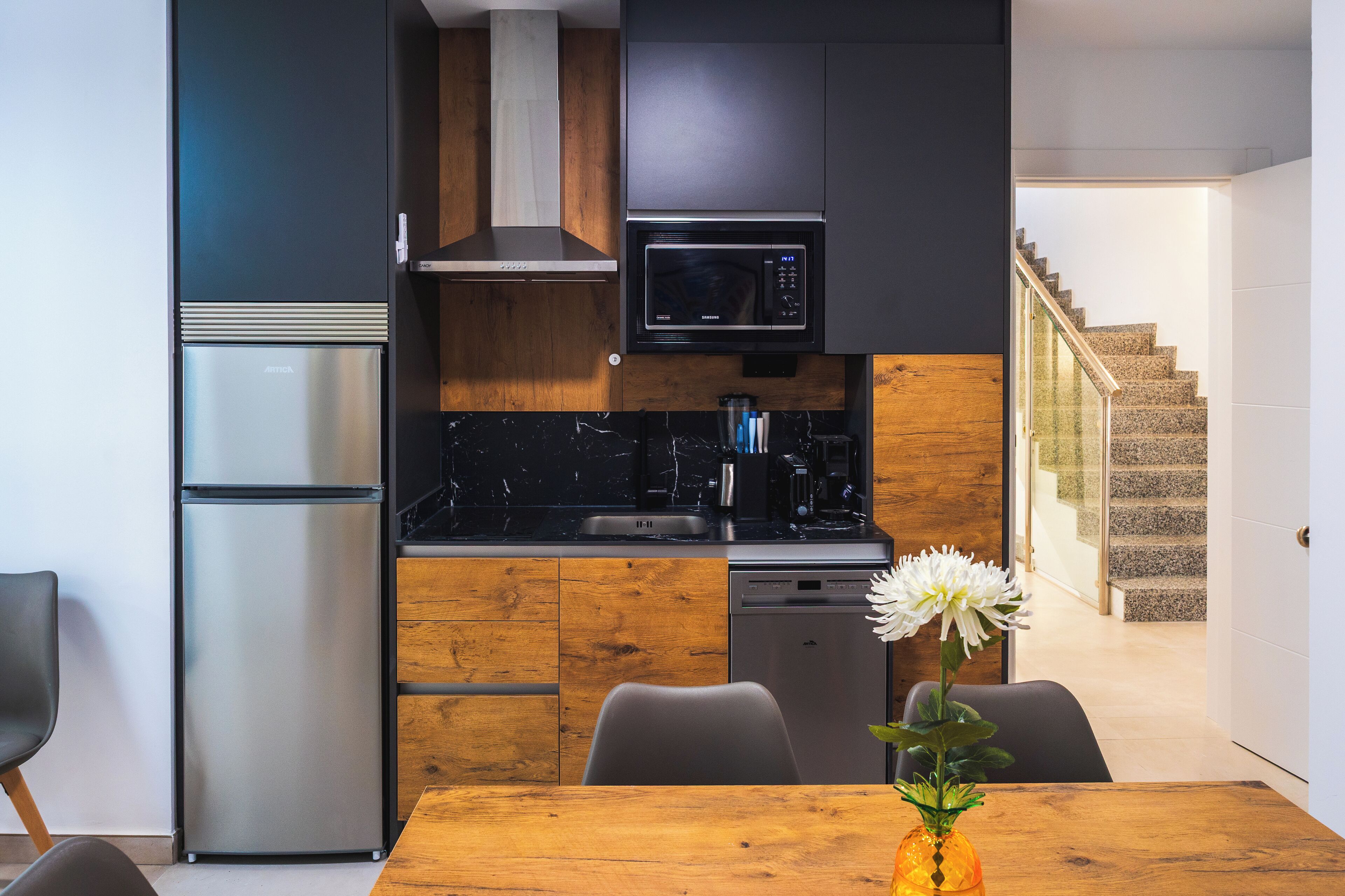 A modern kitchen with a stainless steel refrigerator, a microwave, and a wooden countertop.