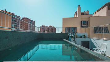 Een buitenzwembad, parasols voor strand/zwembad