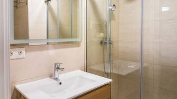Une salle de bain moderne avec une douche à parois de verre, un lavabo blanc et un meuble-lavabo en bois.