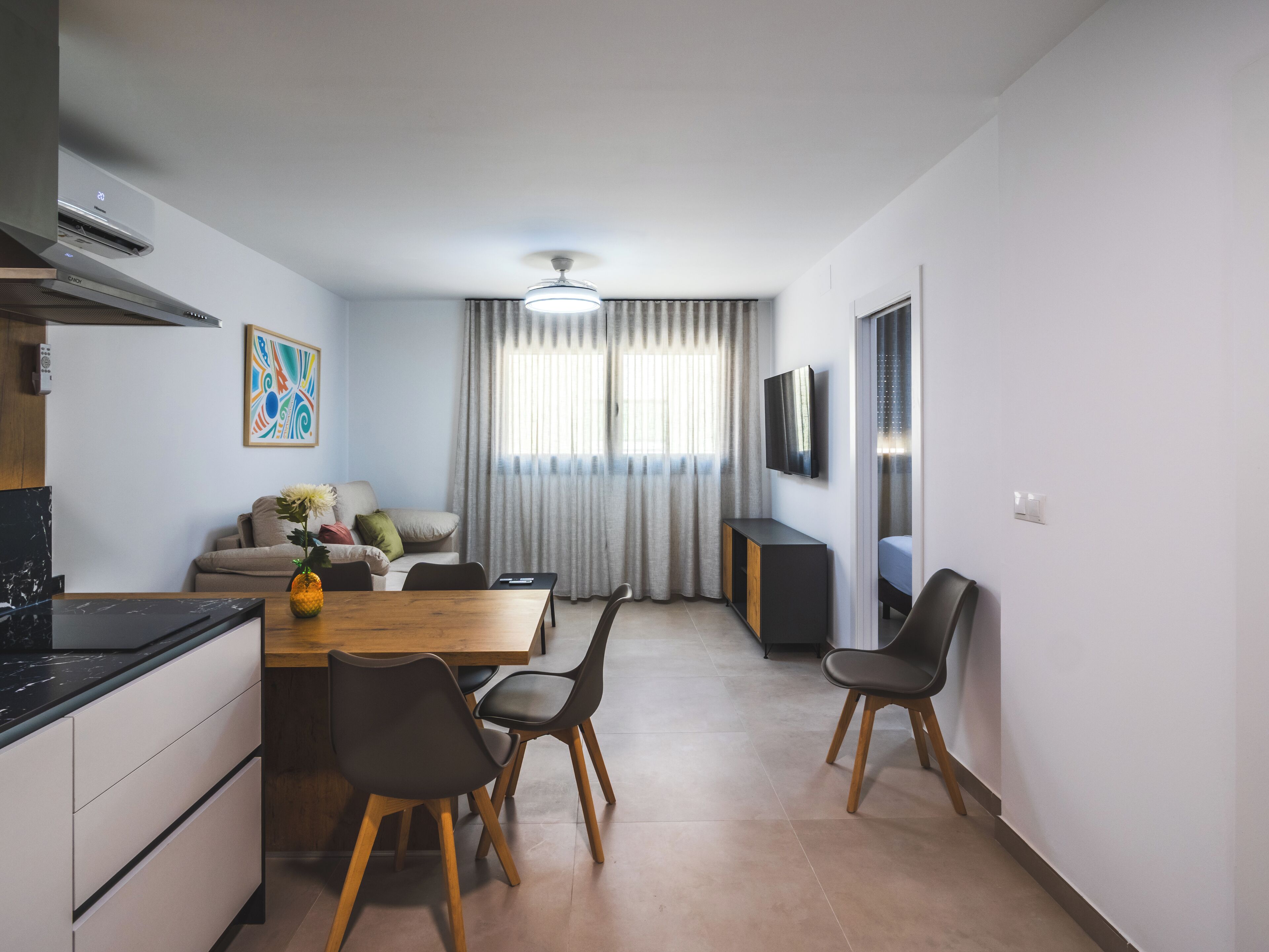 Una cocina moderna con comedor, sofá y televisor.