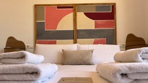A hotel room with a bed, towels, a pillow, and a decorative wall panel.