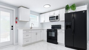 A modern kitchen with white cabinets, a black refrigerator, a microwave, and an oven.