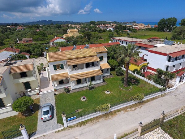 A two-story building with a tiled roof, surrounded by greenery and a clear sky. - DOLPHIN APARTMENTS & STUDIOS (Corfu)