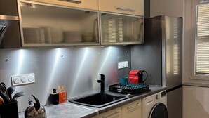 Une cuisine compacte dotée d’appareils électroménagers en acier inoxydable, d’un four encastré et d’un lave-linge.