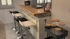 Une cuisine avec un coin bar, un plan de travail en granit, des tabourets de bar et un panier en fil métallique.