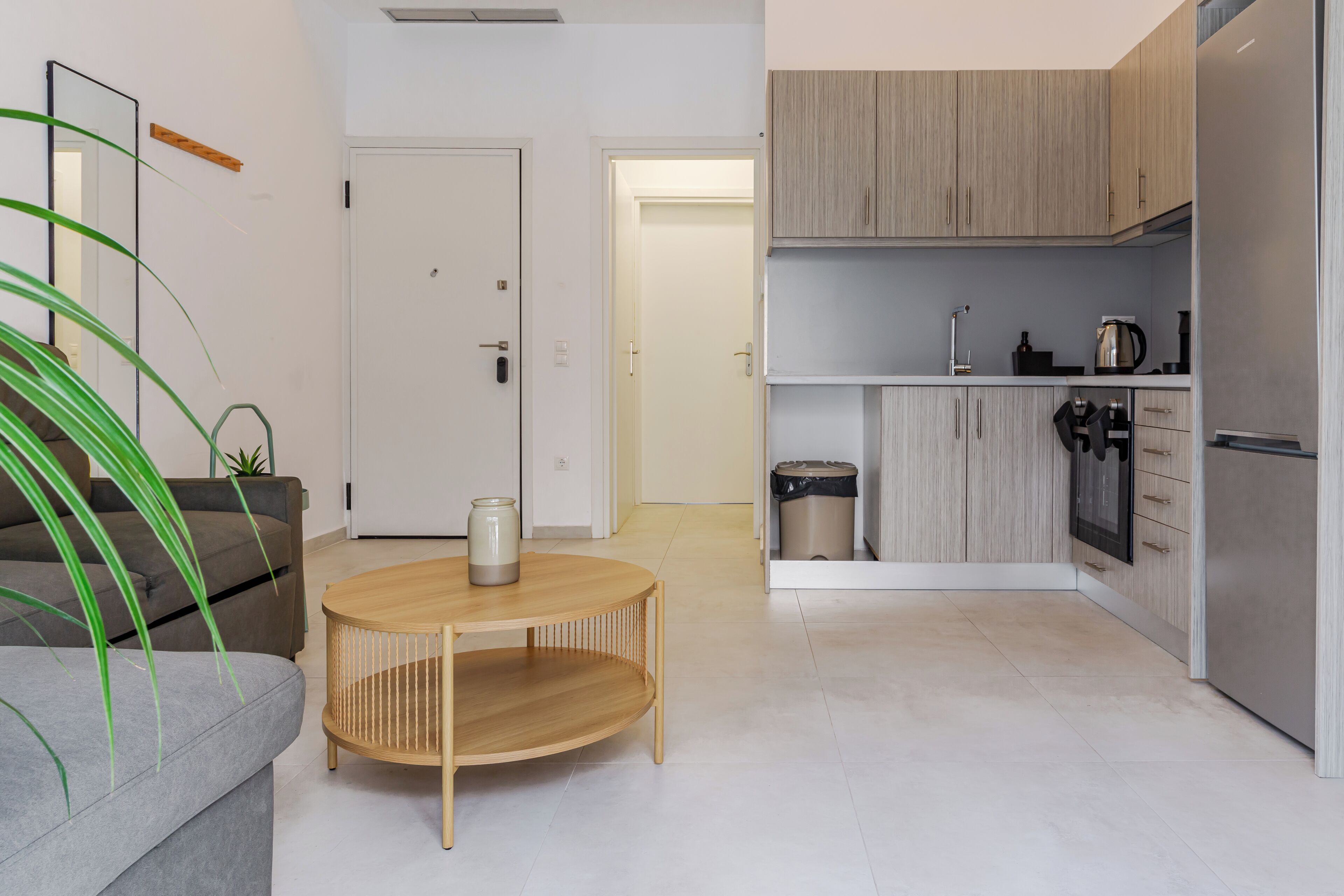 Una cocina moderna con armarios de madera clara, un refrigerador de acero inoxidable y una pequeña zona de encimera.