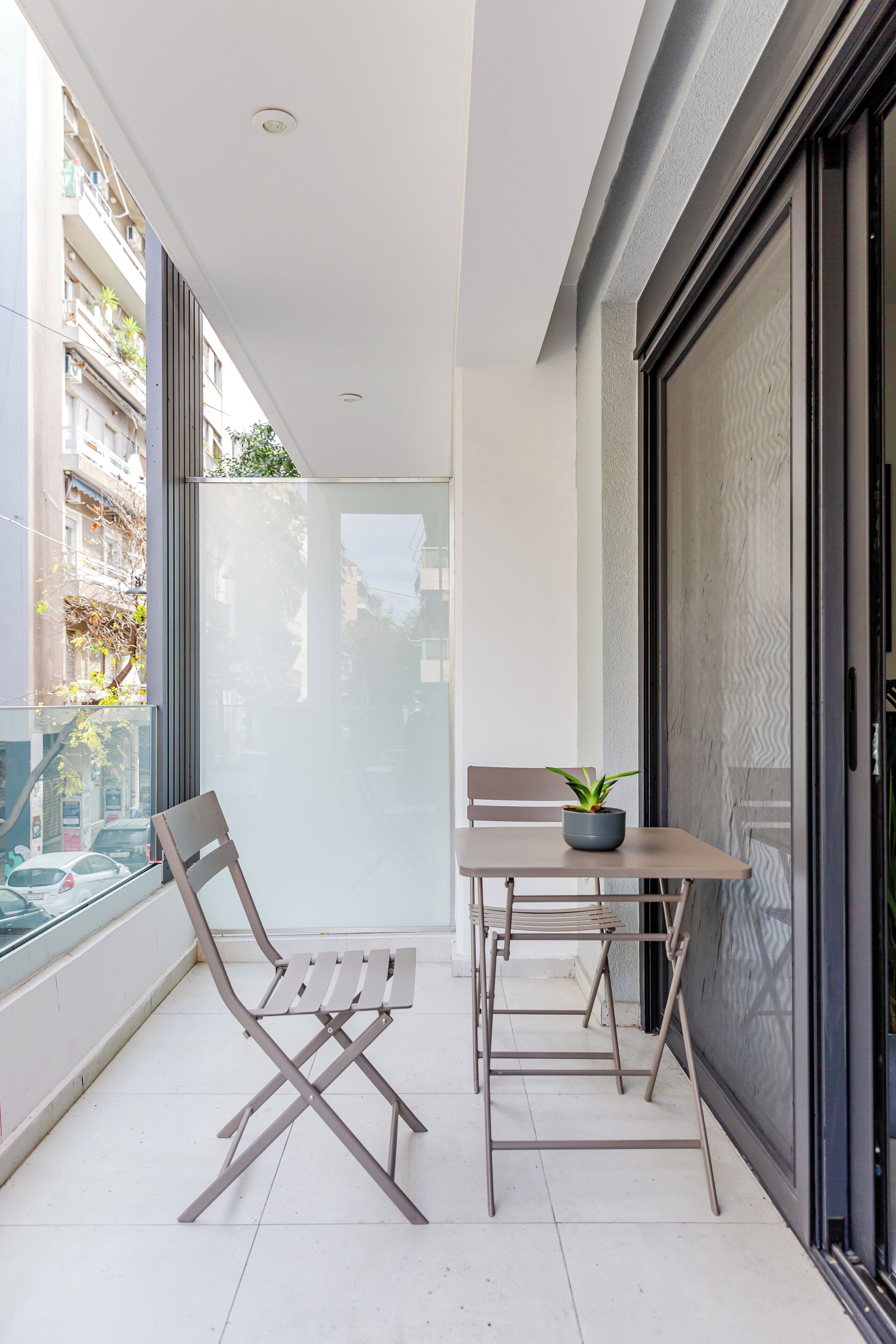 Un balcón con una mesa, sillas y una planta en maceta.