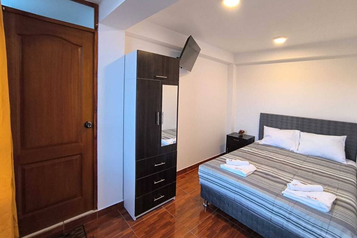 Ein Schlafzimmer mit Bett, Kleiderschrank, Nachttisch und Tür.