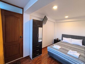 Un dormitorio con una cama, un armario, una mesita de noche y una puerta.