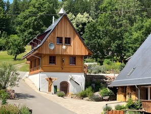 A wooden chalet with a sloped roof, a satellite dish, and a stone pathway leading to the entrance.