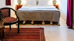 A bedroom with a bed, two bedside lamps, a patterned rug, a chair, and a decorative ceiling. - Beautiful 2-bedroom house "19th century Douiria" in Marrakech-with large terrace (Marrakech)