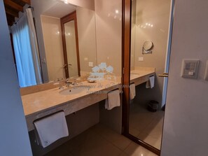 Een badkamer met een grote spiegel, een wastafel en een douche.